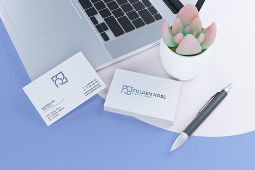 موکاپ کارت ویزیت لوکس سفید در کنار لپتاب و خود نویس و گلدان 